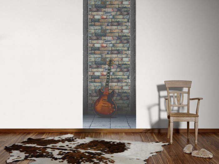 Ein Foto von dem 3D-Fotopanel Gitarre vor Steinwand tapeziert an der Wand. Bestelle Deine Bildtapete online.