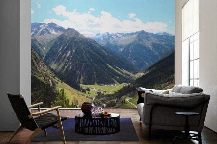 Im Wohnzimmer die Fototapete Alpen Österreich, Tal der Berge auf einer großen Wand tapeziert. Die Fototapete Alpen Österreich, Tal der Berge ist als Vlies-Fototapete im Wohnzimmer leicht zu tapezieren.
