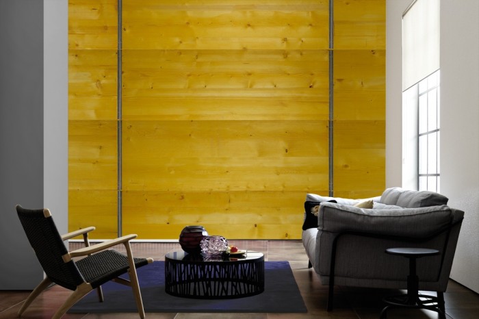 Im Wohnzimmer die Fototapete Holz Wand, gelbe Bretter auf einer großen Wand tapeziert. Die Fototapete Holz Wand, gelbe Bretter ist als Vlies-Fototapete im Wohnzimmer leicht zu tapezieren.