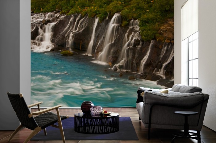 Im Wohnzimmer die Fototapete Wasserfall in Island, Hraunfossar auf einer großen Wand tapeziert. Die Fototapete Wasserfall in Island, Hraunfossar ist als Vlies-Fototapete im Wohnzimmer leicht zu tapezieren.