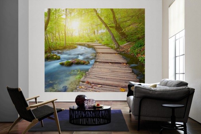 Die Fototapete Holzsteg im Wald als große Bildtapete im Wohnzimmer. Als Bildtapete ist die Fototapete Holzsteg im Wald ein besonderes Highlight auf Vliestapete.