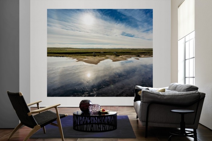 Die Fototapete Landschaft mit Schafen im Sonnenschein als große Bildtapete im Wohnzimmer. Als Bildtapete ist die Fototapete Landschaft mit Schafen im Sonnenschein ein besonderes Highlight auf Vliestapete.