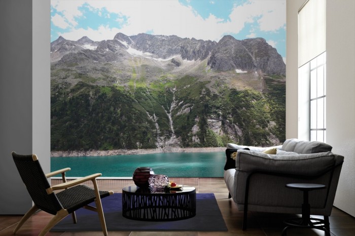 Im Wohnzimmer die Fototapete Alpen Österreich, Bergsee auf einer großen Wand tapeziert. Die Fototapete Alpen Österreich, Bergsee ist als Vlies-Fototapete im Wohnzimmer leicht zu tapezieren.