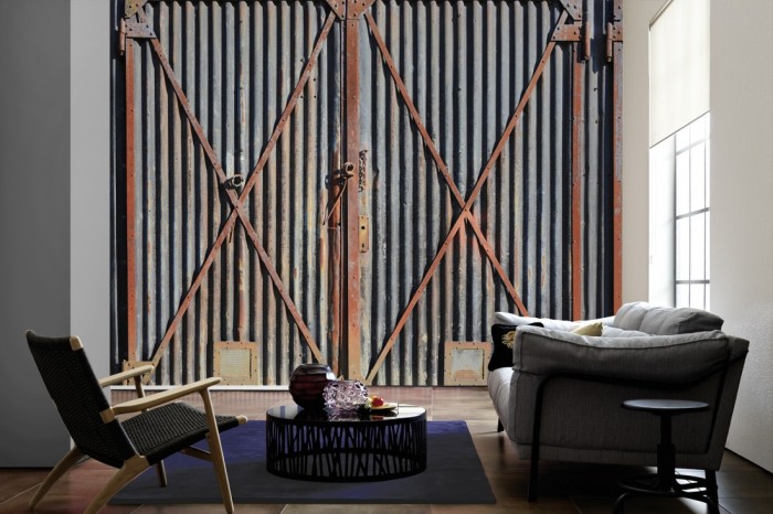 Im Wohnzimmer die Fototapete Rost Wand, Containertüren auf einer großen Wand tapeziert. Die Fototapete Rost Wand, Containertüren ist als Vlies-Fototapete im Wohnzimmer leicht zu tapezieren.