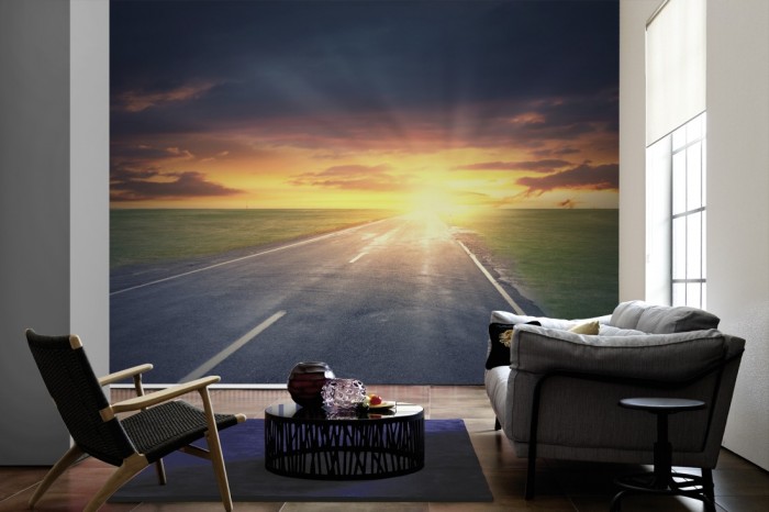 Im Wohnzimmer die Fototapete Straße bei Sonnenaufgang auf einer großen Wand tapeziert. Die Fototapete Straße bei Sonnenaufgang ist als Vlies-Fototapete im Wohnzimmer leicht zu tapezieren.
