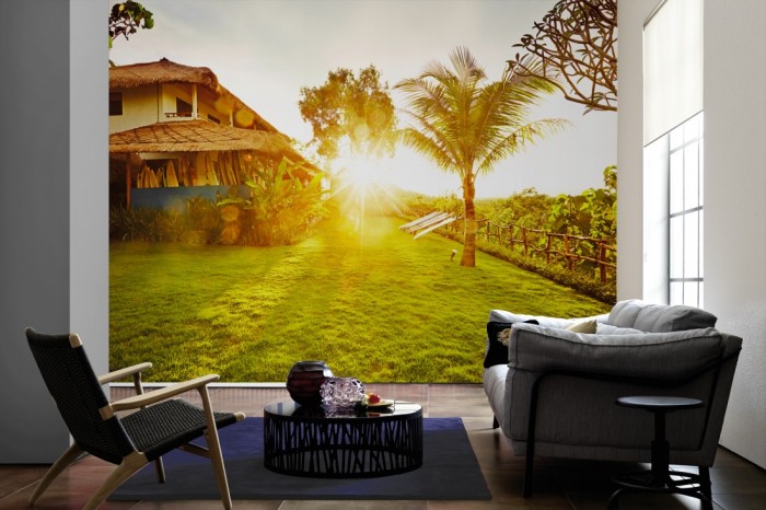 Im Wohnzimmer die Fototapete Bali, Haus und Garten bei Sonnenuntergang auf einer großen Wand tapeziert. Die Fototapete Bali, Haus und Garten bei Sonnenuntergang ist als Vlies-Fototapete im Wohnzimmer leicht zu tapezieren.