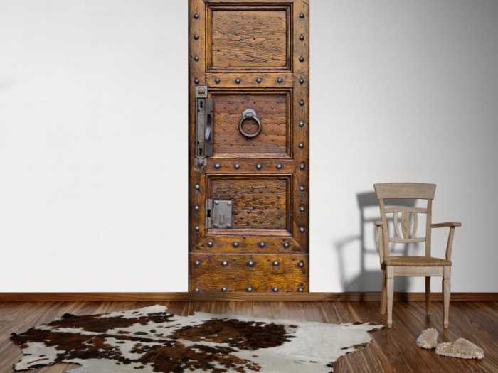Ein Foto von dem 3D Fotopanel Alte Holztür aus Eiche mit Nieten tapeziert an der Wand. Bestelle Deine Bildtapete online.